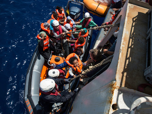 Crew from a Sea Watch search and rescue vessel rescue survivors from a boat that foundered trying to cross the Mediterranean to Europe from Libya in 2016.