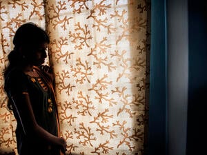 Photo of a refugee woman captured standing by the window by Natalia Lazaro