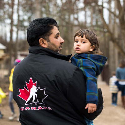 Canada. Mohammad, a Syrian refugee man carrying his youngest son at a petting zoo