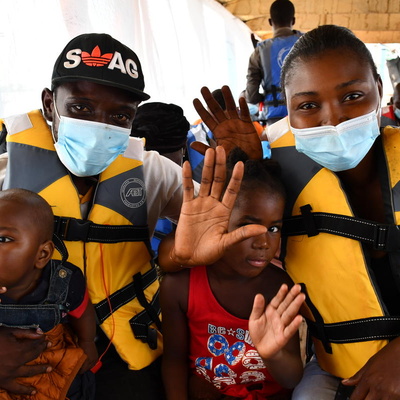 Central African returnees wave as the boat carrying them back to their homeland leaves Zongo in the Democratic Republic of the Congo, November 2020.