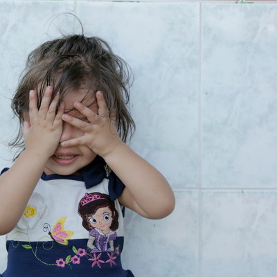 A young girl cover her eyes with her hands