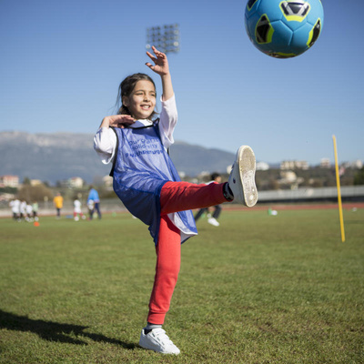 Young girl kicks ball during a refugee solidarity event. National football associations across Europe are stepping up to help welcome refugees into their new communities.