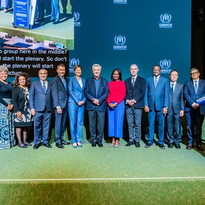 A group of people, including UN High Commissioner for Refugees Filippo Grandi, stand on a stage