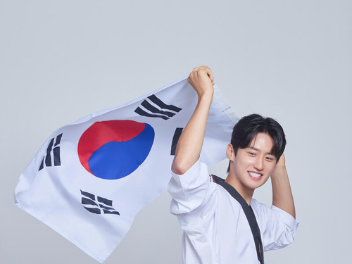 Daehoon Lee waves a Korean flag while wearing a taekwondo uniform