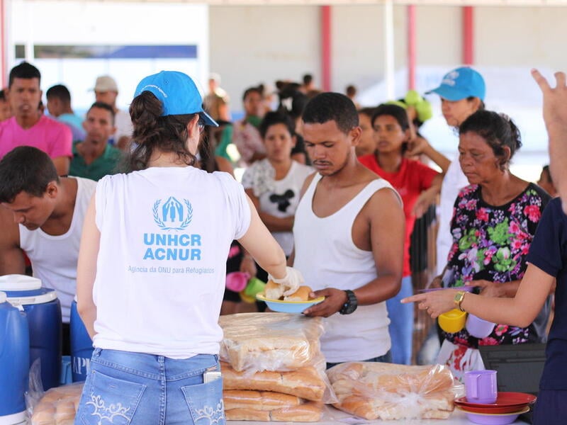 A UNHCR staff member serves bread to Venezuelan families.
