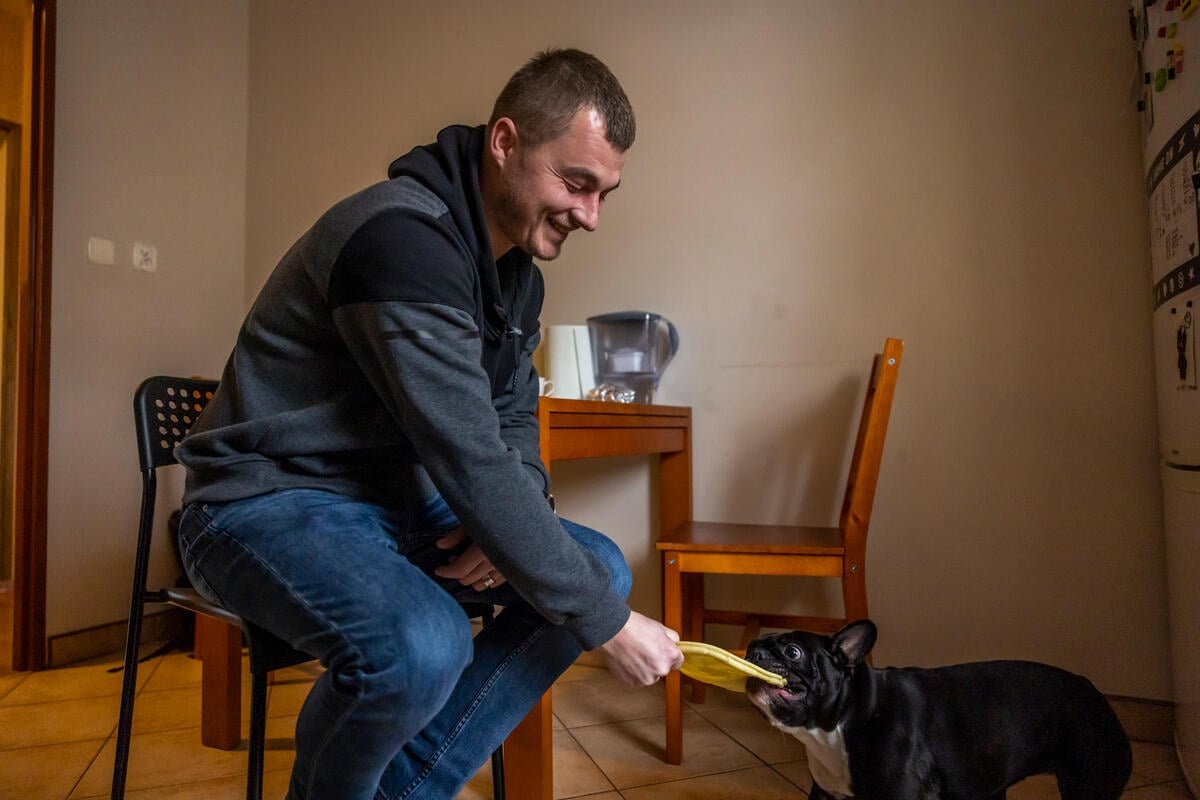 A man plays with his dog in his kitchen.