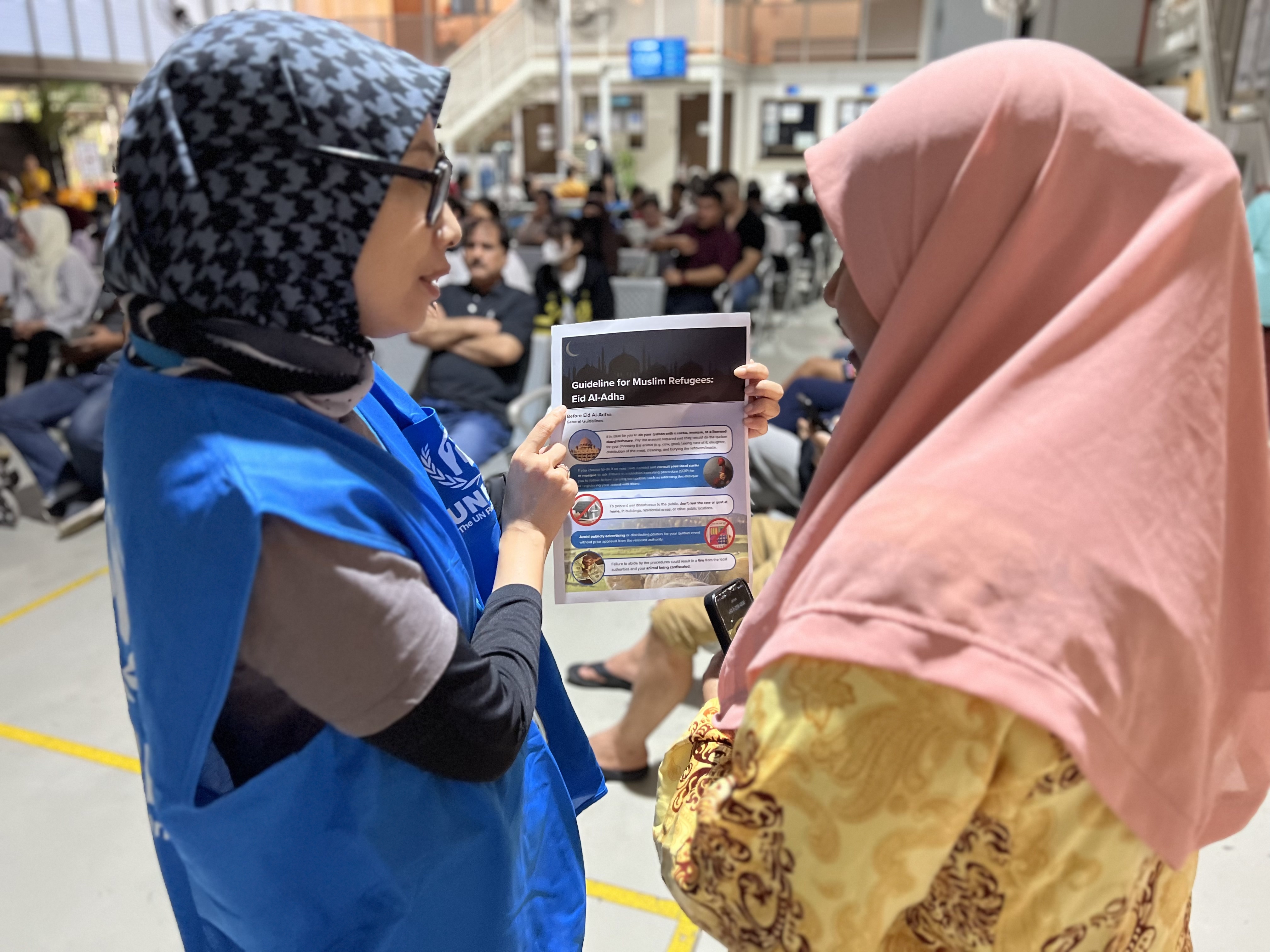 UNHCR staff sharing qurban guidelines with a refugee at UNHCR Malaysia 