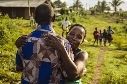 A Côte d'Ivoire refugee is embraced by his aunt upon returning home