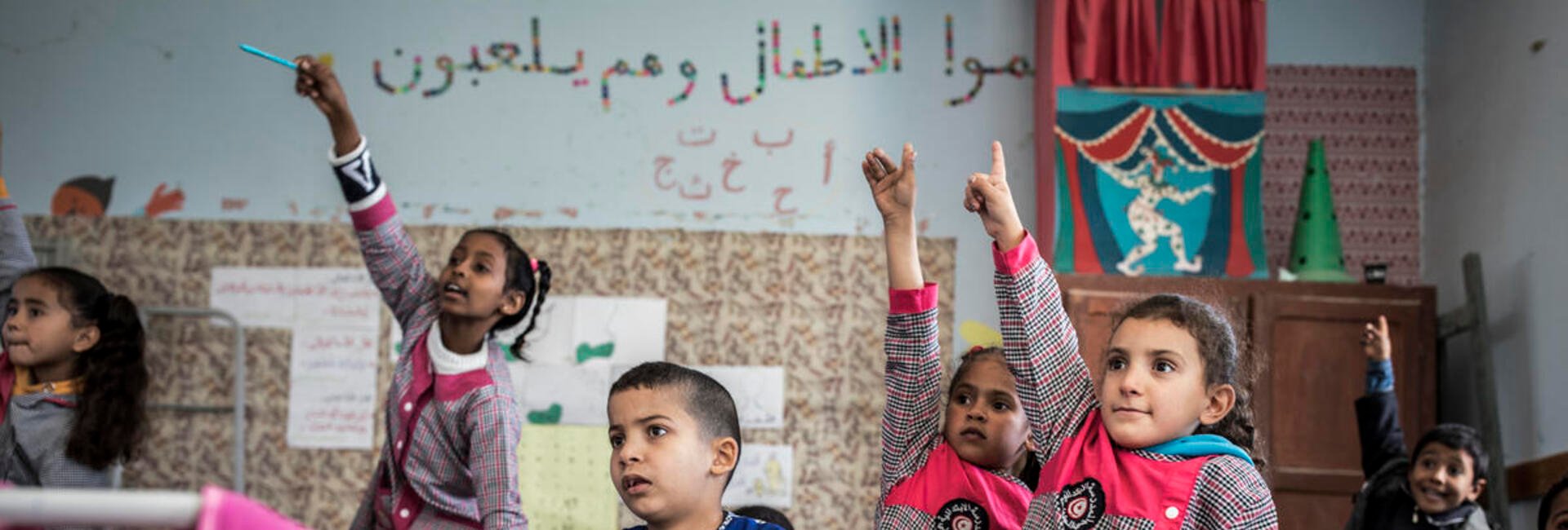  Eritrean refugee children raise their hands in a classroom in Tunisia. 