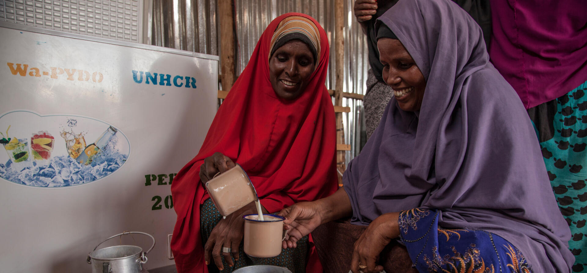 Ethiopia. Refugee women measure cups of milk to sell