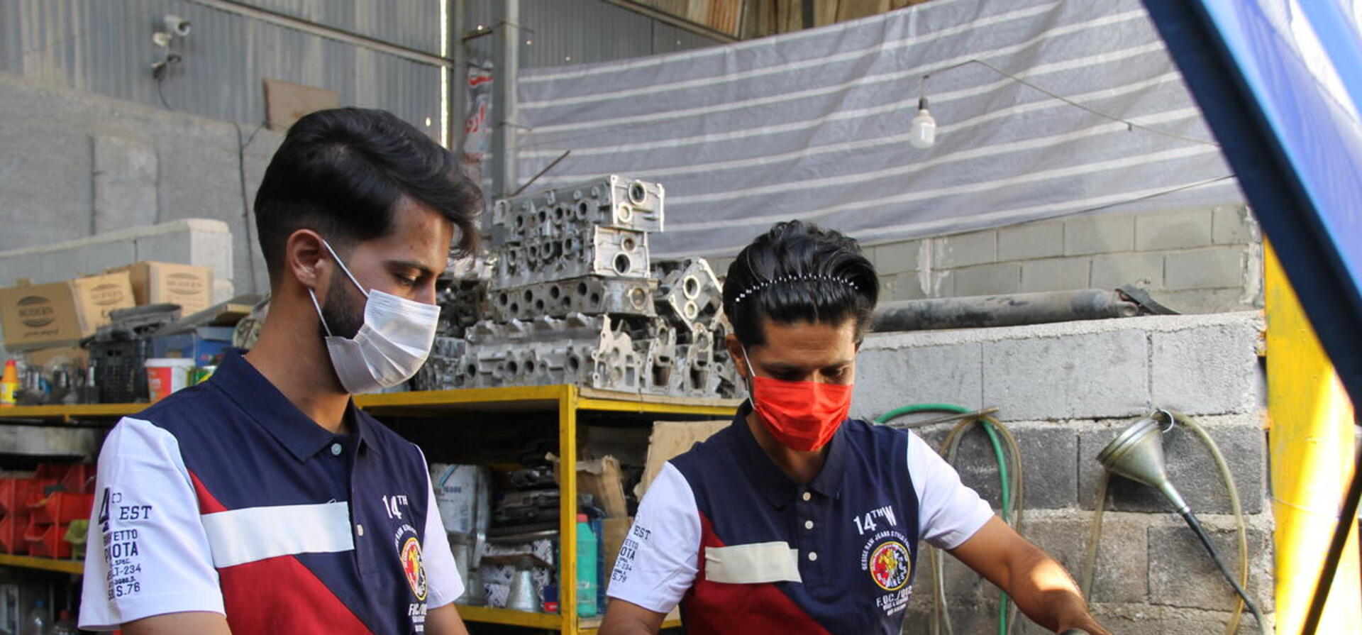 Iran. Afghan refugee and Iranian business partner in their automobile repair shop supported by UNHCR