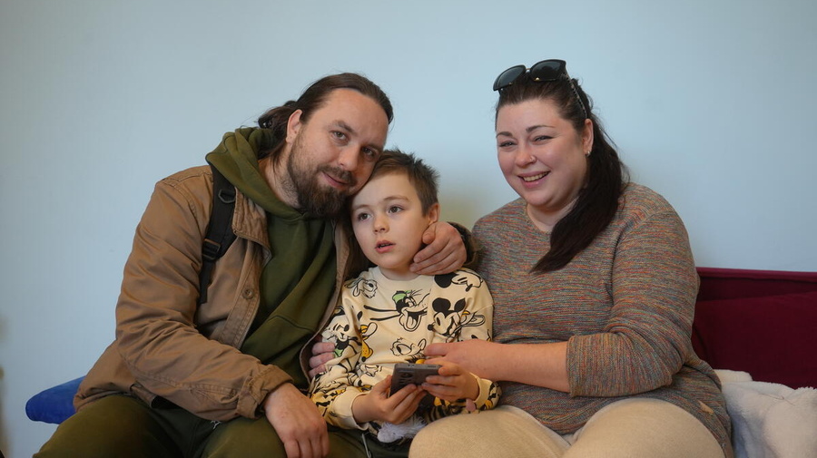 Two parents and a six-year-old boy are pictured smiling, their arms around each other