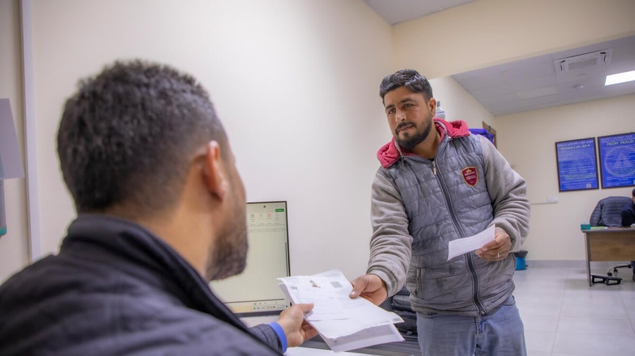 A Syrian refugee living in Iraq receives official documents from a UNHCR staff member.