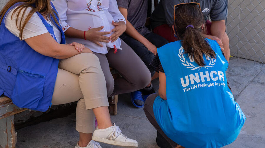 Two UNHCR staff members speak with asylum-seekers in a border town in northern Mexico.