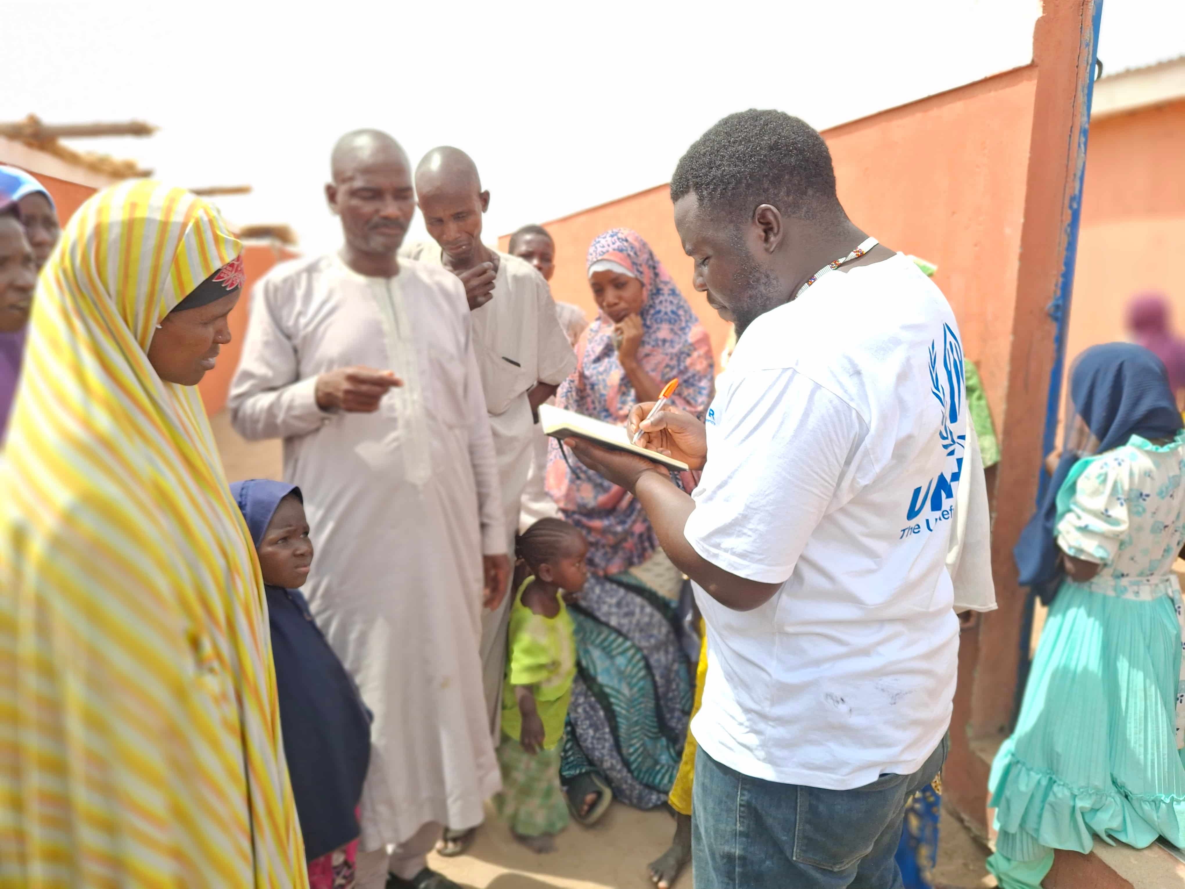 UNHCR Field Associate Iliya Ishira speaks with community members during a field visit to Banki, Borno State, northeast Nigeria.