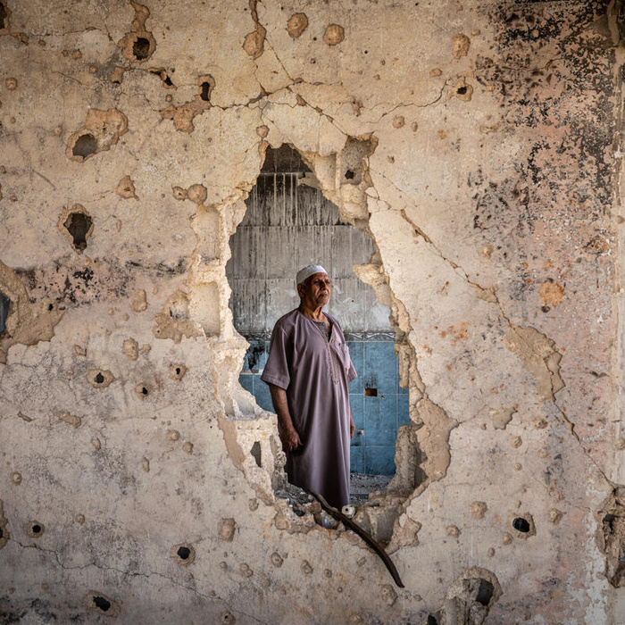 Ikrimah Ahmad Al-Sarrees, een teruggekeerde vluchteling, staat in een deels beschadigde kamer in zijn huis in Daraa, Zuid-Syrië.