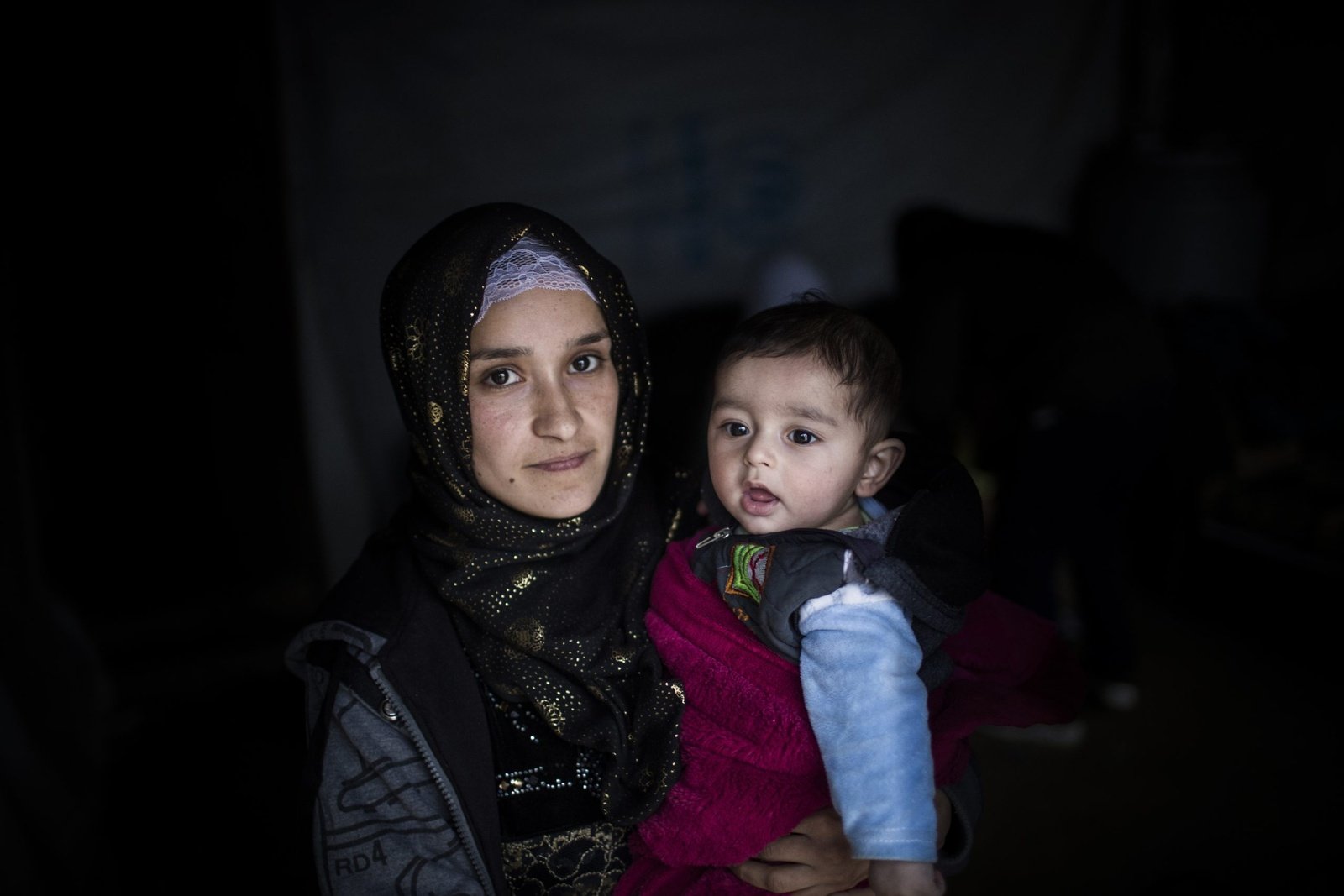 Hakima, 21, uit Deir ez-Zor in Oost-Syrië, met haar baby Jad in de vluchtelingennederzetting Bar Elias in centraal Libanon. Hakima is al vijf jaar in Libanon en woont met haar man in het huis van haar zwager, nadat dat van hen overstroomde tijdens storm Norma. © UNHCR/Diego Ibarra
