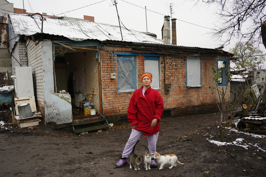 Ukrainian lady in front of a bombed house