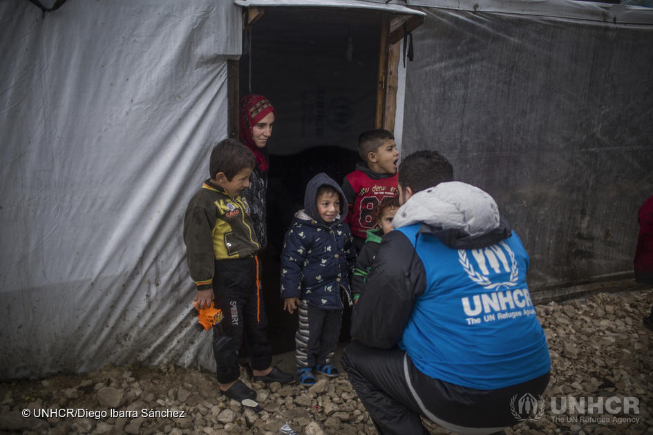 Een UNHCR medewerker praat met een groepje jongens in een vluchtelingenkamp in de Bekaa Vallei