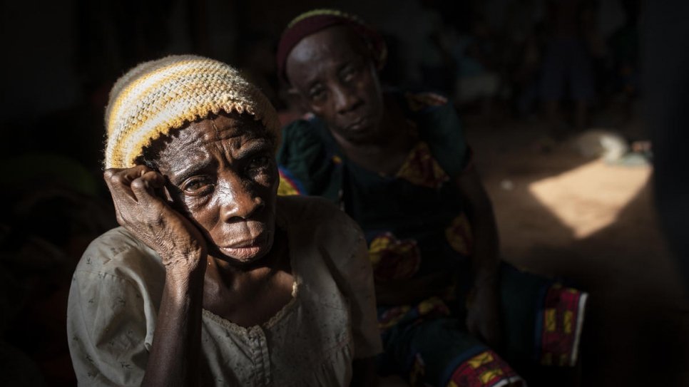 Een oudere vrouw zit in een ruimte waar Engelstalige vluchtelingen uit Kameroen wachten om te worden over geplaatst naar het Agadom Refugee Settlement in Ogoja, Nigeria. © UNHCR/Will Swanson