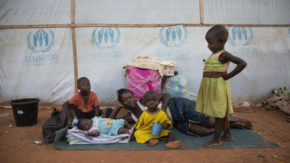 Een Engelstalige vluchtelingenfamilie uit Kameroen wordt buiten op een mat wakker bij het Agadom Refugee Settlement in Ogoja, Nigeria. © UNHCR/Will Swanson