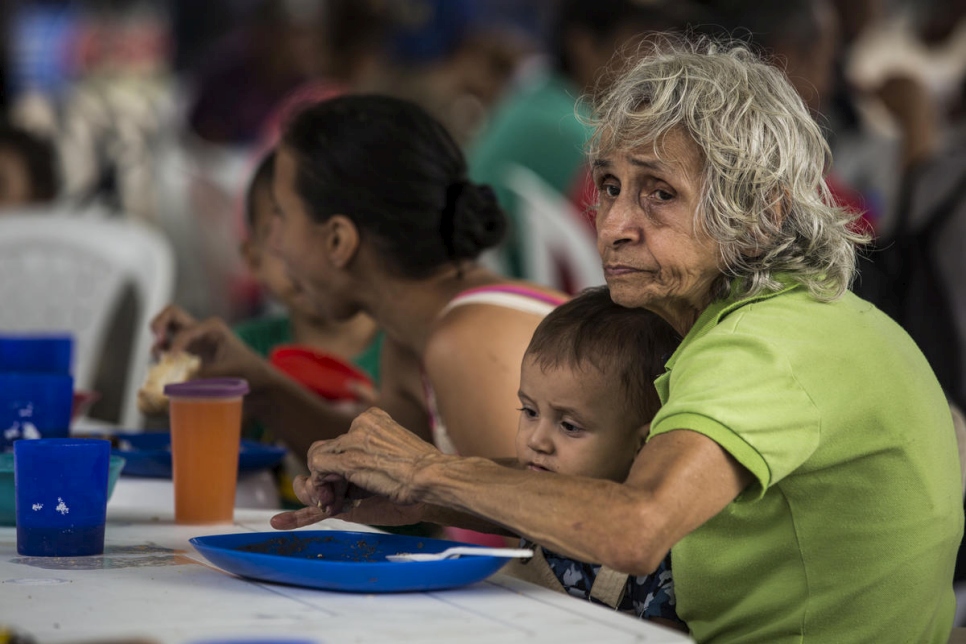 Een Venezolaanse grootmoeder en haar kleinzoon eten een maaltijd in een gemeenschappelijke keuken in Cúcuta, Colombia, april 2019. © UNHCR/Vincent Tremeau