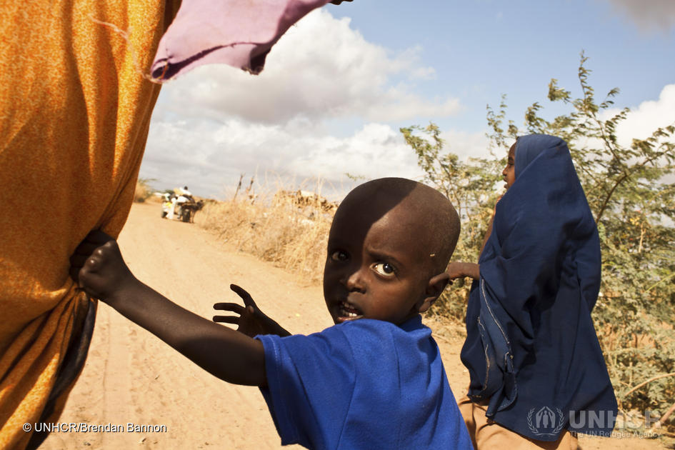 Een moeder en haar twee kinderen volgen een ezelskar vol met de bezittingen van het gezin en verhuizen naar een uitbreiding van het Ifo-gebied in Dadaab, Kenia. Het is het grootste vluchtelingenkamp ter wereld. Ze maken deel uit van een uittocht uit Somalië als gevolg van een aanhoudende burgeroorlog en de gevolgen van droogte en hongersnood. Juli 2011 © UNHCR/Brendan Bannon