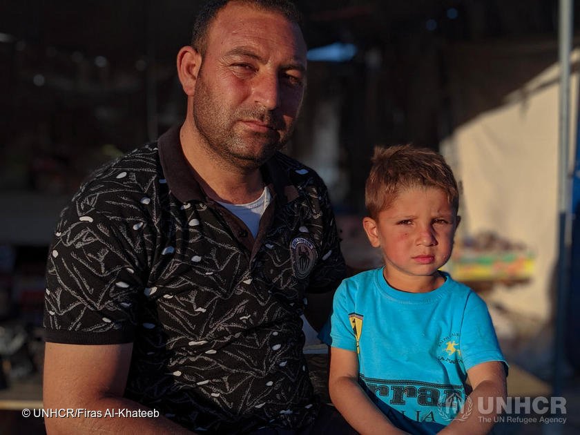 Mustafa en zijn zoon zitten buiten zijn geïmproviseerde supermarkt in het Bardarash Refugee Camp, Irak. © UNHCR/Firas Al-Khateeb
