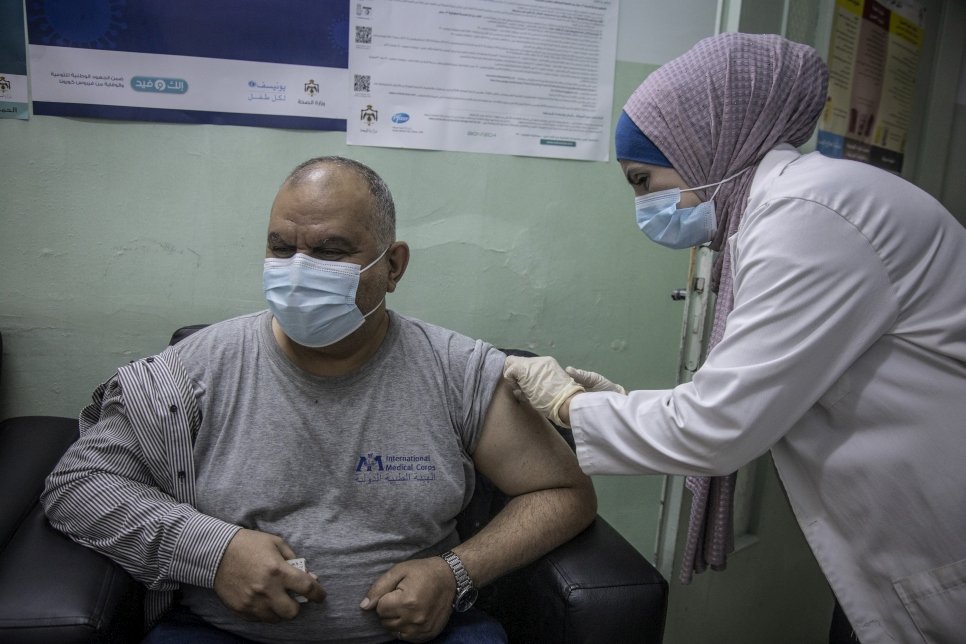 Een medisch medewerker dient een dosis van het COVID-19-vaccin toe in de vaccinatiekliniek Irbid in Jordanië. © UNHCR/Jose Cendon