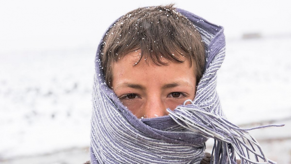 Een jonge Syrische vluchteling pakt zich goed in tegen de kou. Bekaa Vallei, Libanon, 2016. © UNHCR/Haidar Darwish
