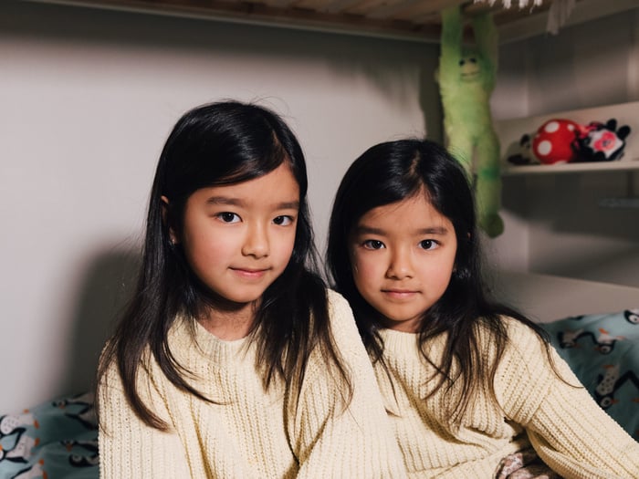 A couple of young girls sitting on a bed