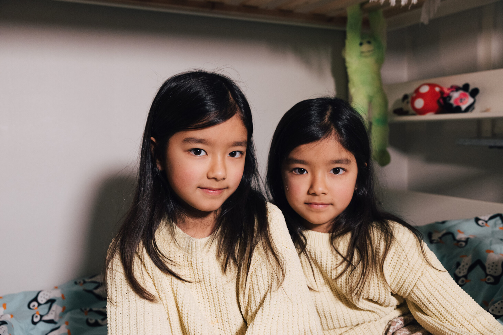 A couple of young girls sitting on a bed