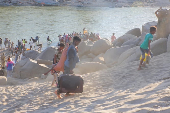 Ethiopian refugees flee across a river with their belongings.