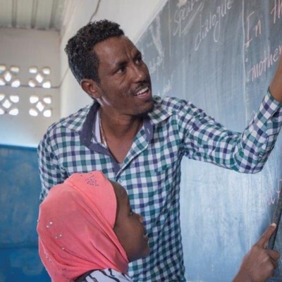 A teacher and his student in front of a black board.