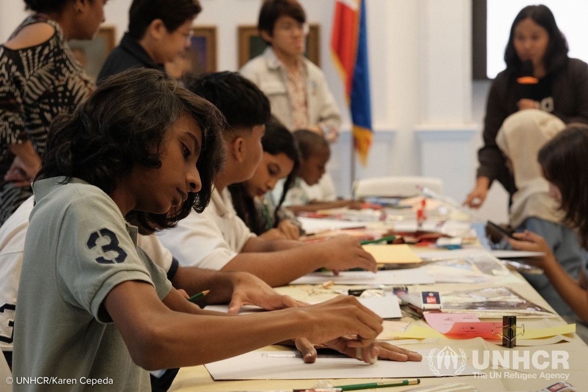 A group of young refugees and asylum seekers gather around a long table