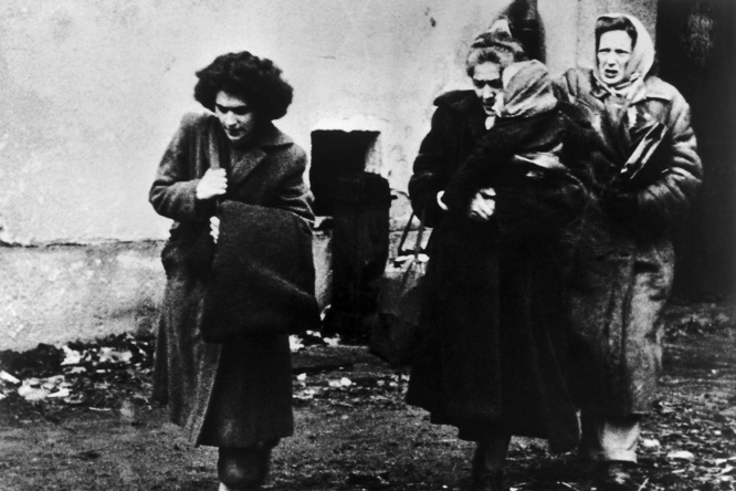 Black and white photo of three women and a child arriving at a refugee camp in Austria.
