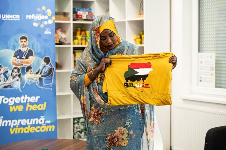 A lady holding a T-shirt with the Sudanese flag