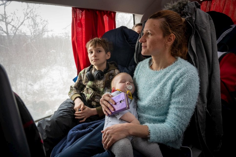 Natalia, în vârstă de 35 de ani, și cei doi copii ai ei călătoresc cu autobuzul spre Huși, în România, după ce au fugit în Republica Moldova din casa lor din Mykolaiv, în sudul Ucrainei. © UNHCR/Mihai Eremia