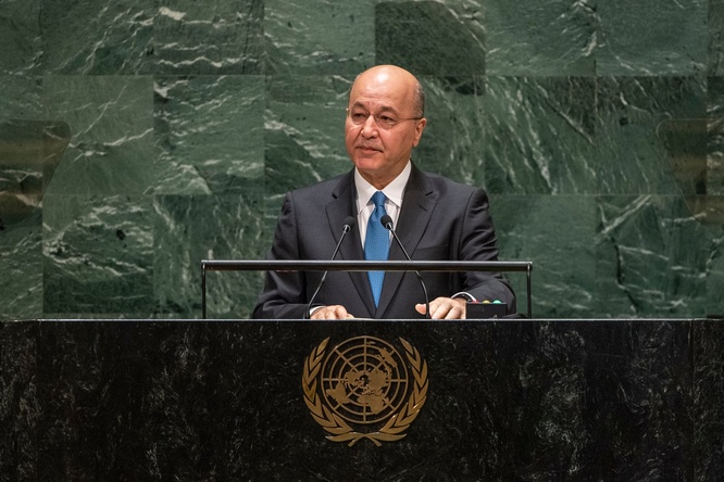 A man in a suit speaks at a podium bearing the United Nations emblem