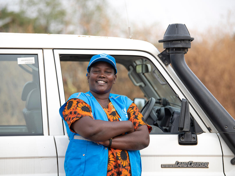  Rose, a UNHCR driver, smiles for the camera as she stands in front of the Landcruiser she drives.
