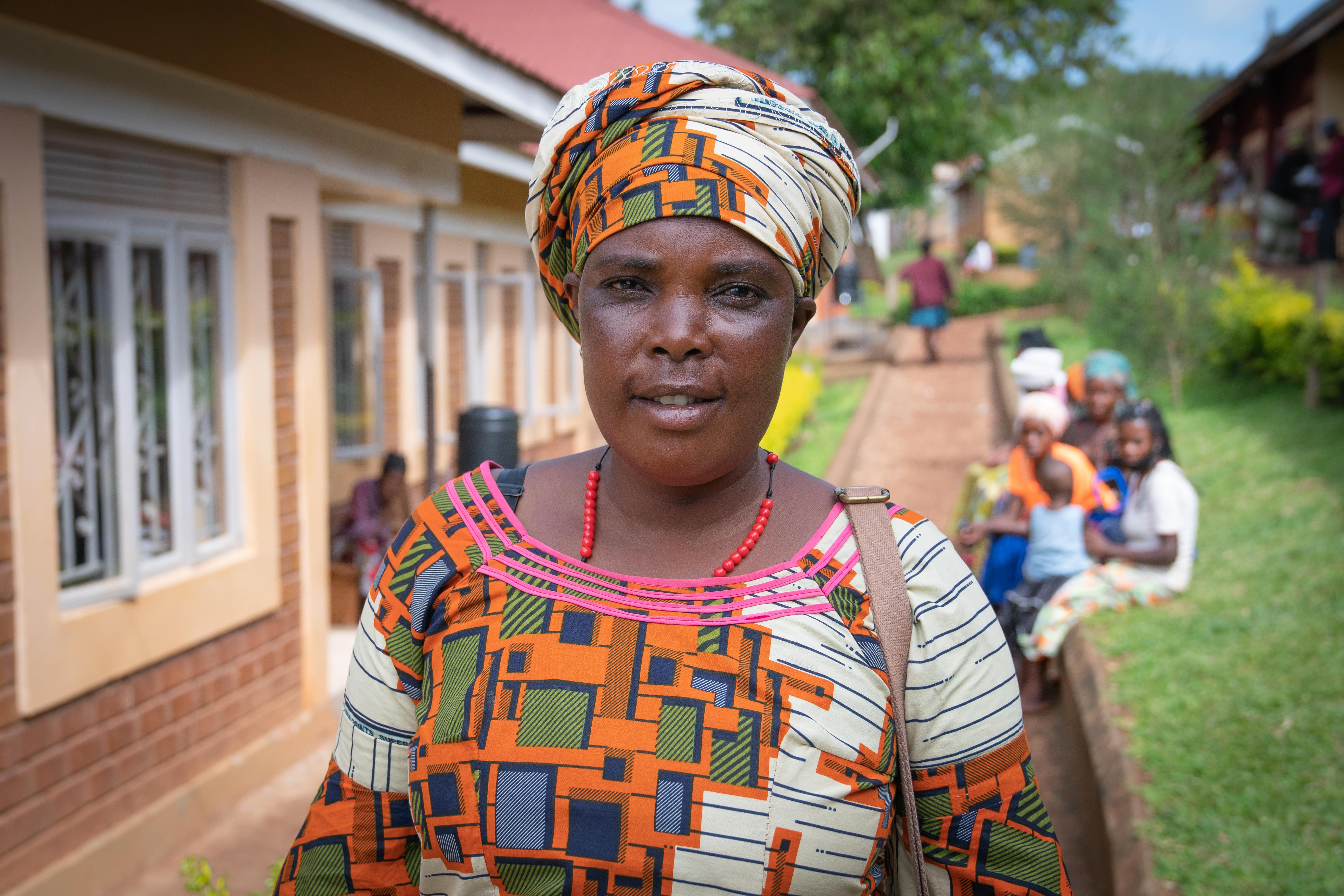 A woman stands on a pathway outside a row of buildings.