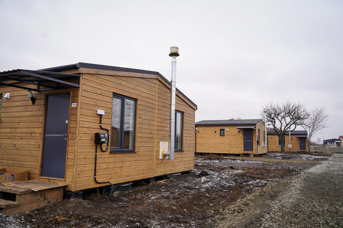 A row of newly-installed wooden-clad prefabricated housing units.