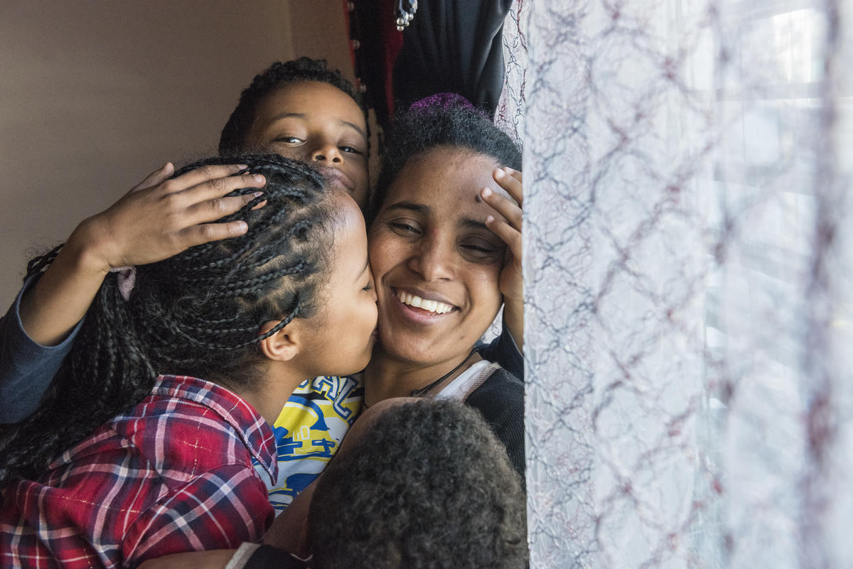 A woman smiles while hugging her three children.