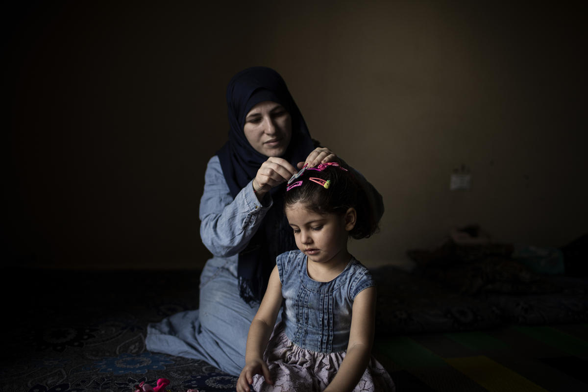 A Syrian woman does her daughter's hair.