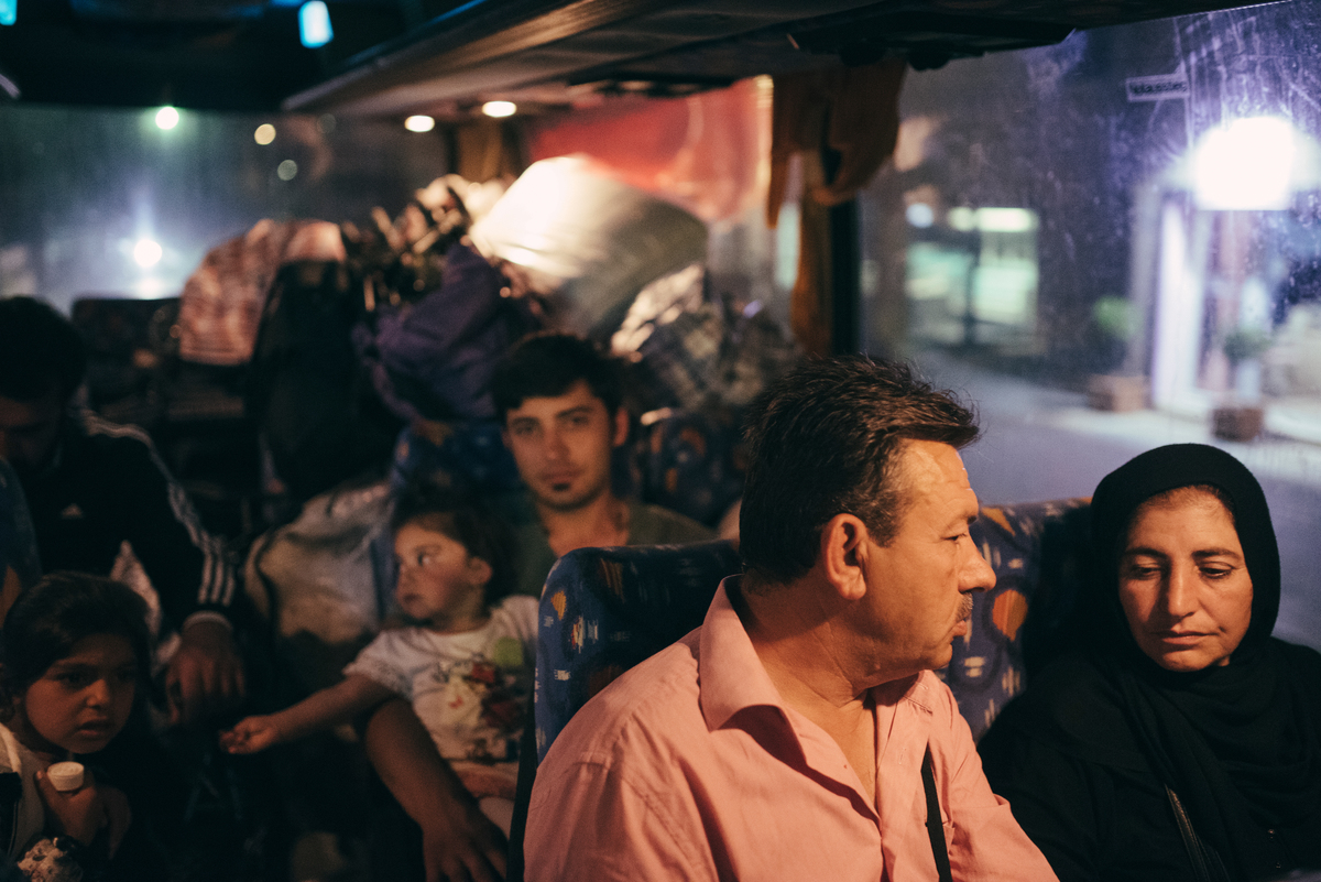 Greece, a group of people being relocated inside a UNHCR bus with all their luggage.