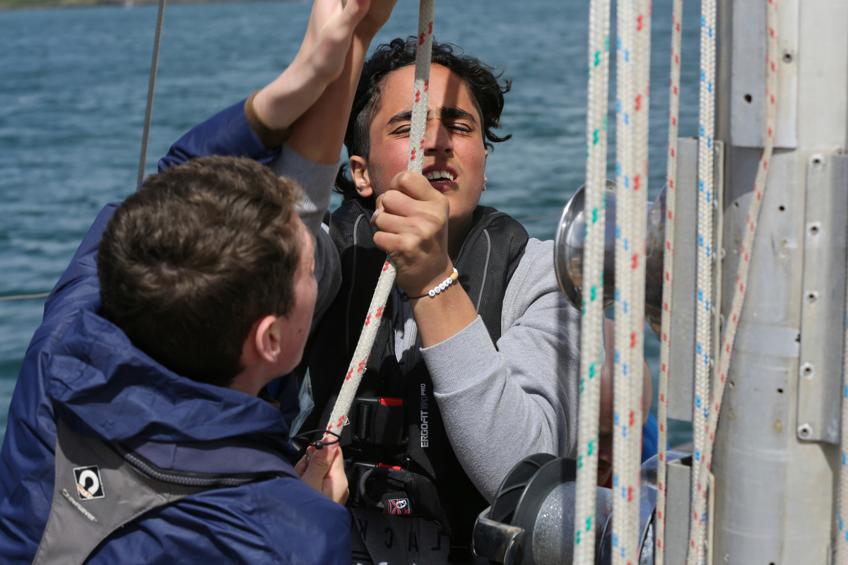 Ireland. A Syrian Asylum Seeker and an Irish teenager working alongside each other on a sail training vessel off the coast of West Cork