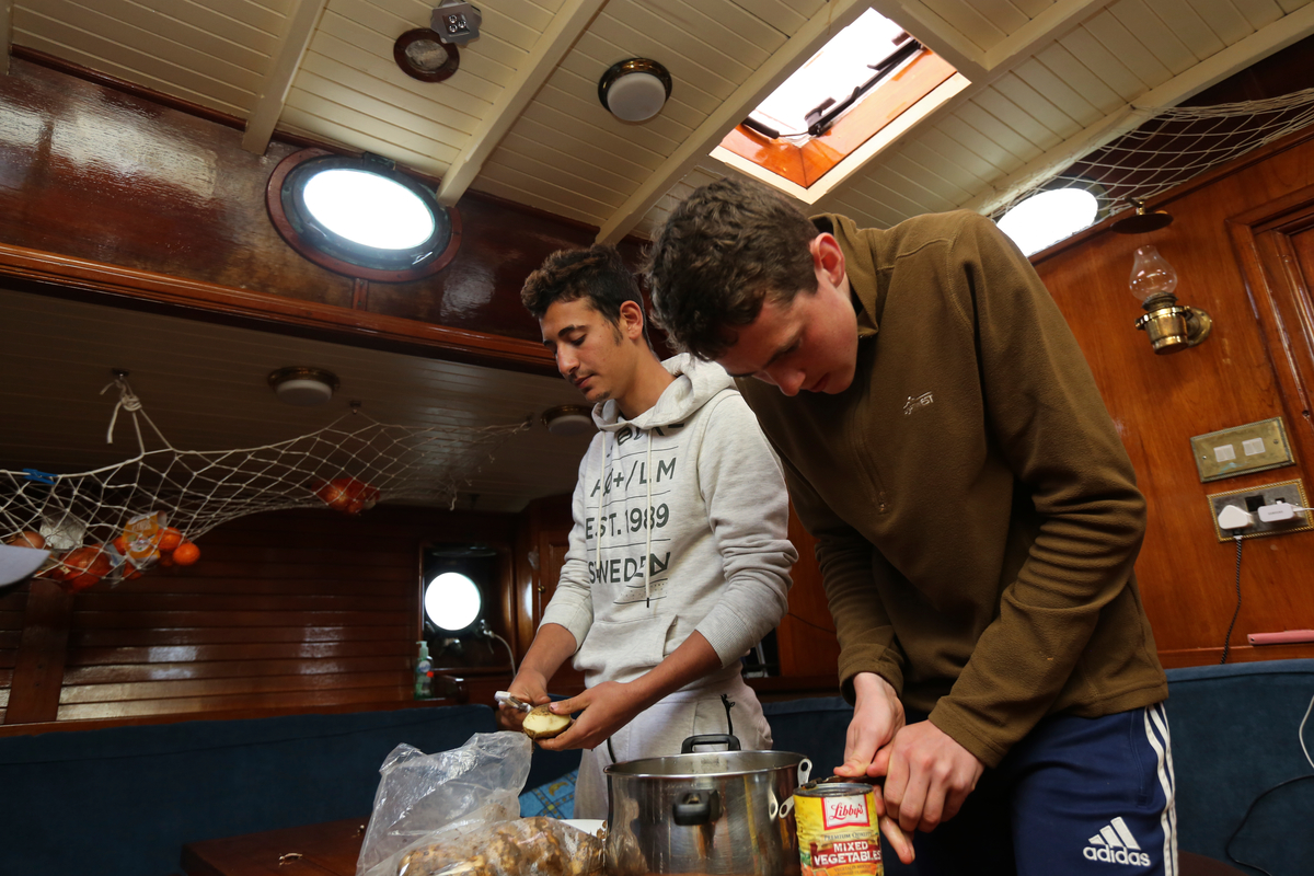 Ireland. A Syrian Asylum Seeker and an Irish teenager preparing dinner on a sail training vessel off the coast of West Cork
