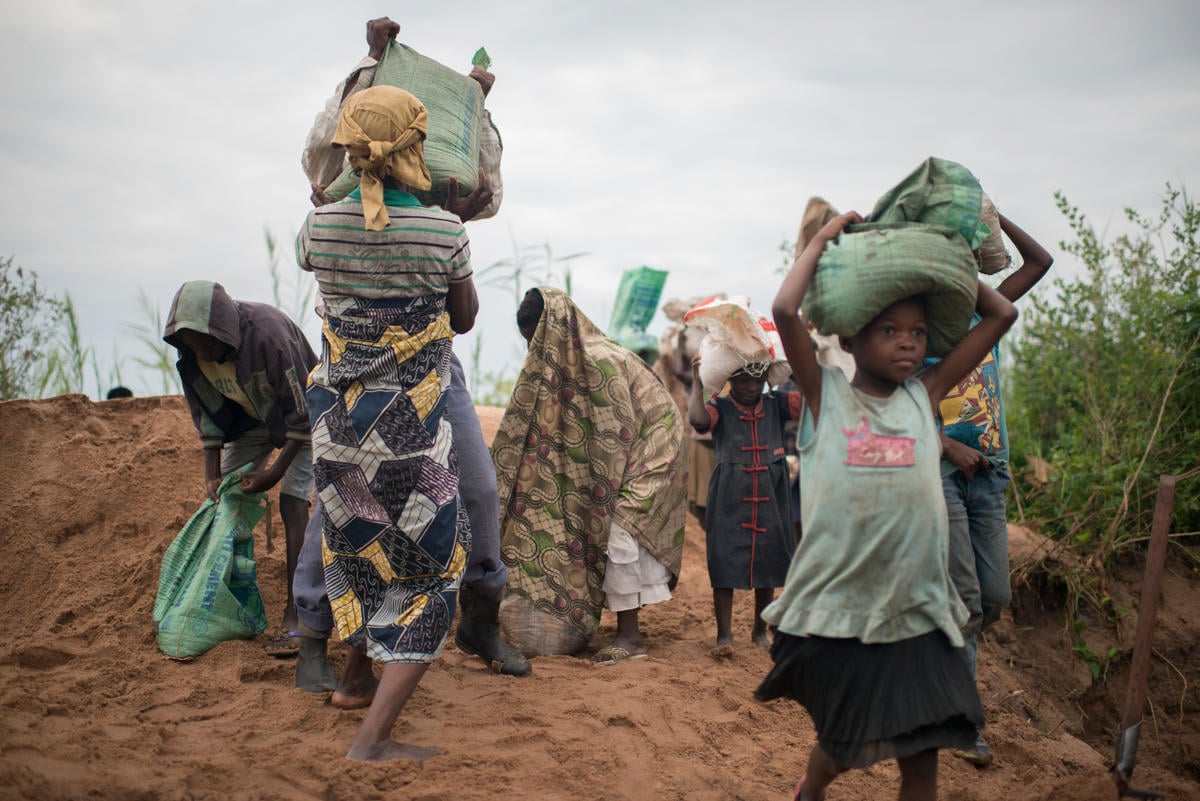 Displaced women and children lift bags of sand to be carried to construction sites in Kalemie, the capital of DR Congo's Tanganyika Province.