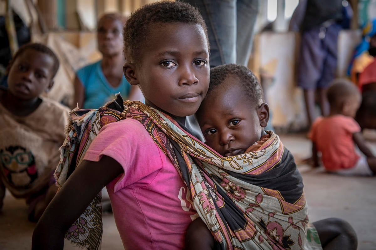 Mozambique. Rosa, age 7, holds her younger brother, Manuel, in a shelter for women and children in Buzi