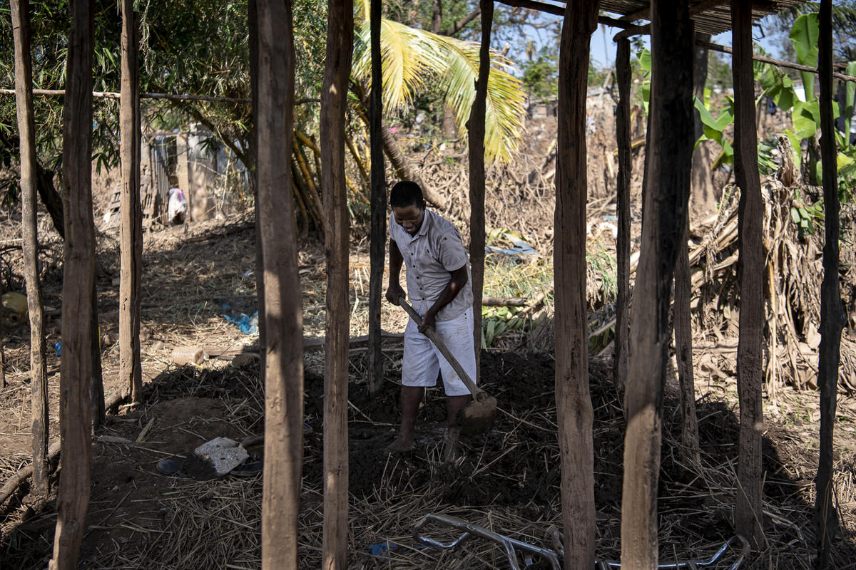 Mozambique. Manuel, a school teach from Buzi, cleans the mud from the foundation of what was his home